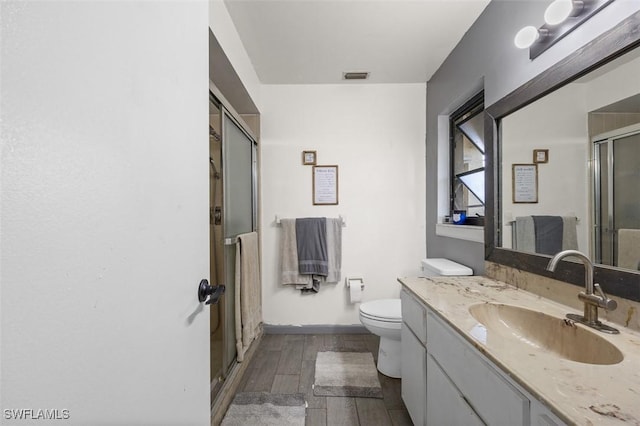 full bath with visible vents, toilet, wood finished floors, a shower stall, and vanity