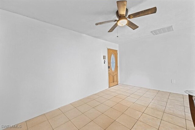 empty room with light tile patterned flooring, visible vents, and ceiling fan