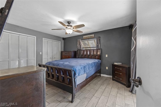 bedroom featuring light wood-style flooring, baseboards, multiple closets, and ceiling fan