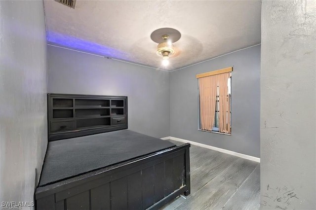 unfurnished bedroom featuring visible vents, wood finished floors, and baseboards