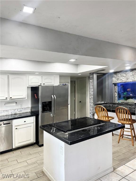 kitchen with white cabinetry, dark countertops, appliances with stainless steel finishes, and wood tiled floor