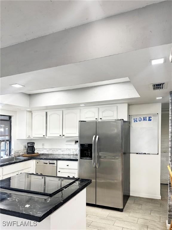 kitchen featuring light wood-style flooring, stainless steel fridge, white cabinetry, black electric cooktop, and a sink