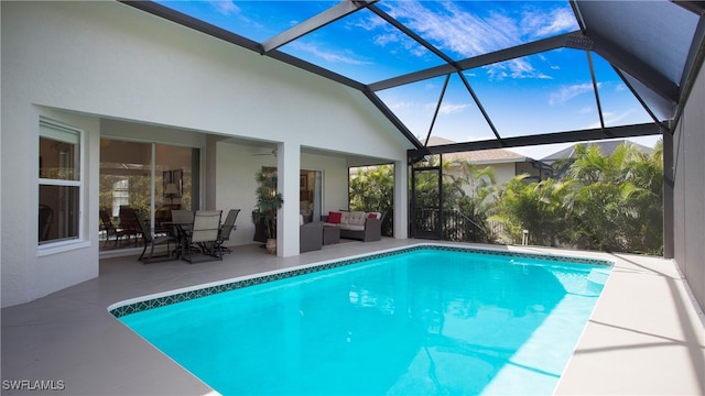 view of pool featuring glass enclosure, ceiling fan, a patio, and an outdoor living space