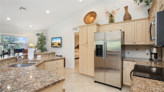 kitchen featuring sink, light stone counters, appliances with stainless steel finishes, tasteful backsplash, and lofted ceiling