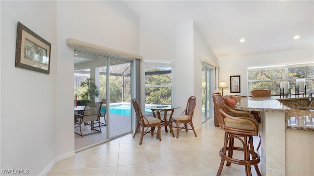 tiled dining room featuring a healthy amount of sunlight and vaulted ceiling