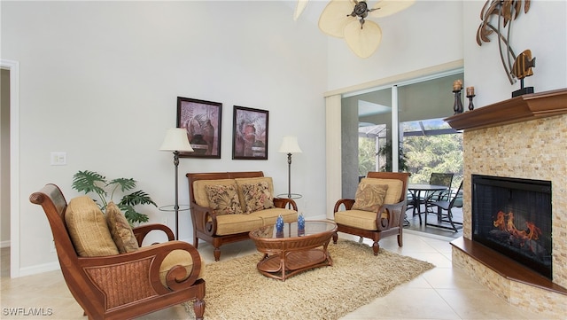 living area featuring ceiling fan, light tile patterned flooring, and a towering ceiling