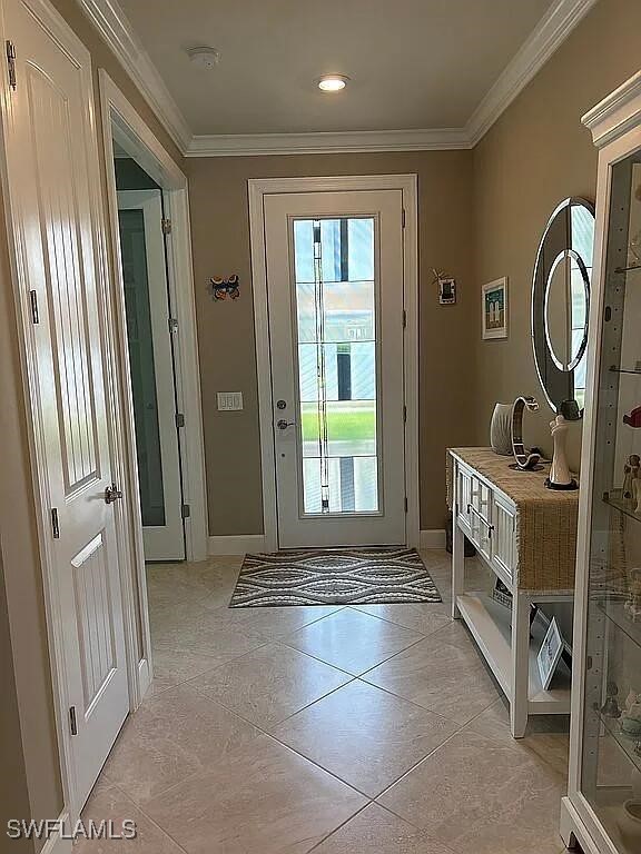 doorway featuring ornamental molding and light tile patterned floors