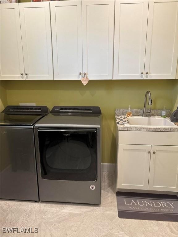 laundry area featuring light tile patterned flooring, cabinets, sink, and washing machine and dryer