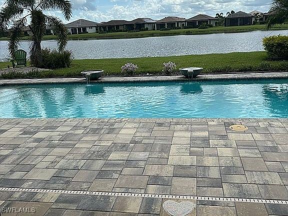 view of pool featuring a water view and a patio area