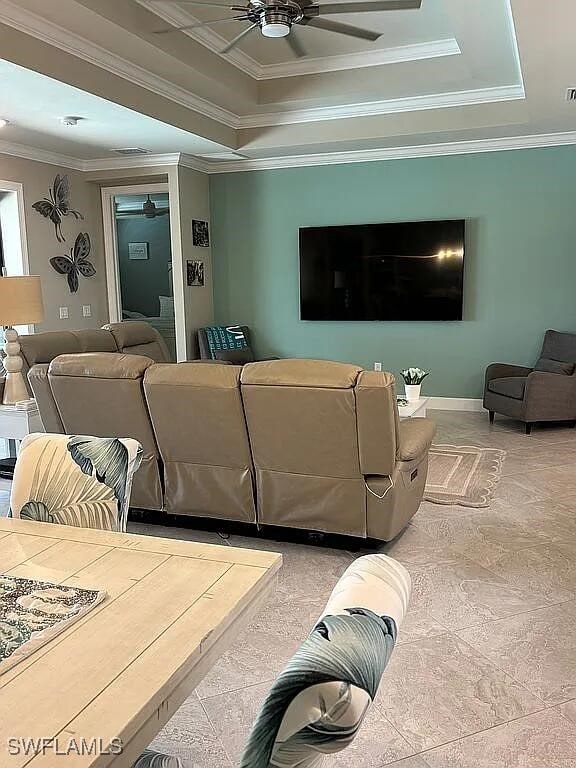 living room with tile patterned flooring, crown molding, and a raised ceiling