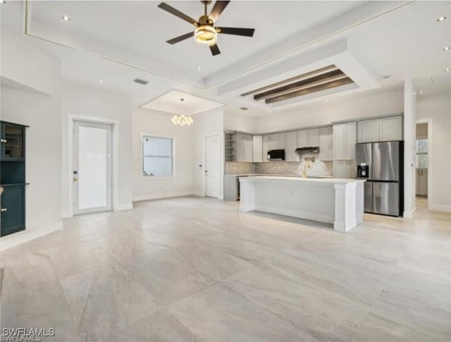 kitchen with appliances with stainless steel finishes, tasteful backsplash, a kitchen bar, ceiling fan, and a kitchen island with sink