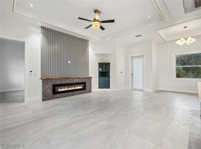 unfurnished living room with ceiling fan and a raised ceiling