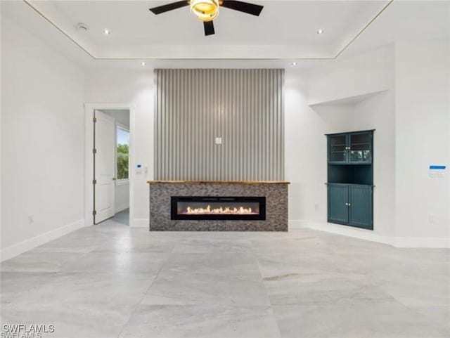 unfurnished living room featuring ceiling fan and a tray ceiling