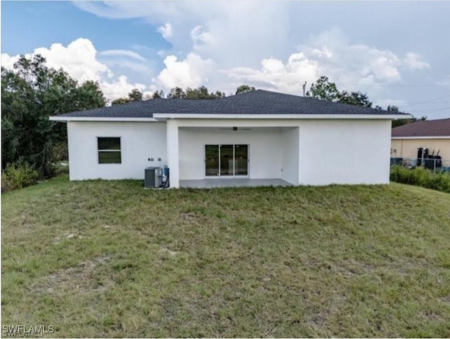 rear view of property featuring central AC and a yard