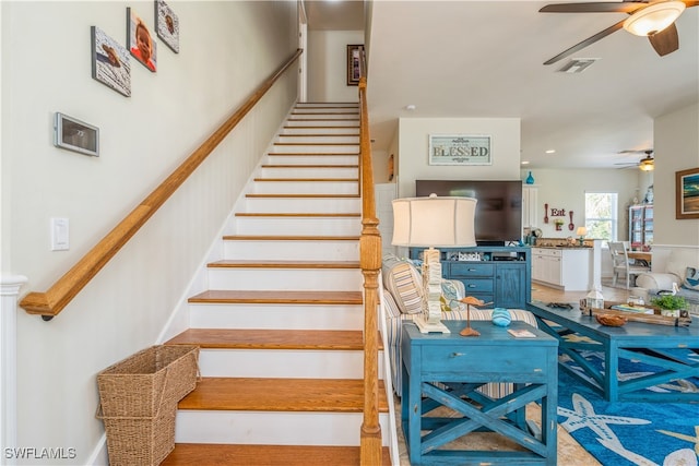 stairway featuring ceiling fan