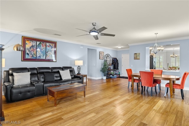 living room with ceiling fan with notable chandelier, ornamental molding, and light hardwood / wood-style flooring