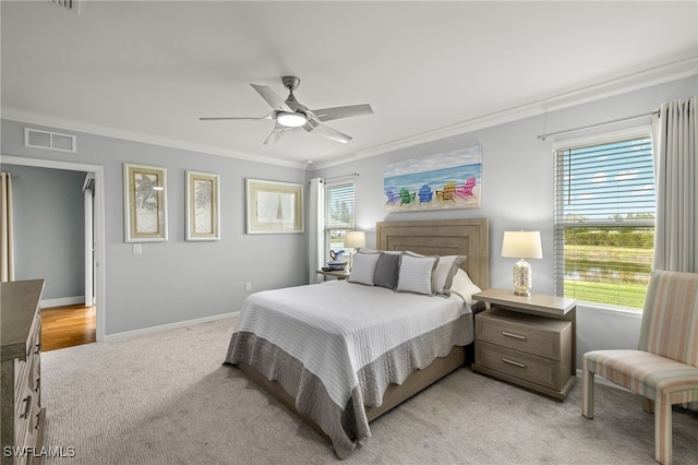 bedroom with ornamental molding, light colored carpet, multiple windows, and ceiling fan