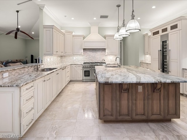 kitchen featuring custom exhaust hood, double oven range, sink, and a large island with sink