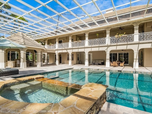 view of swimming pool featuring an in ground hot tub, a lanai, ceiling fan, and a patio area