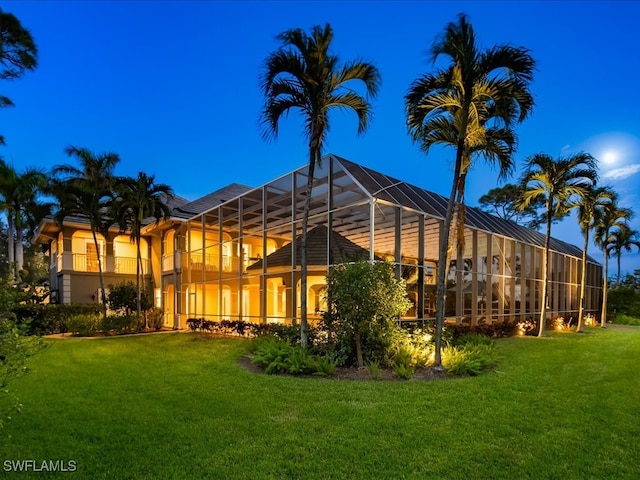 back of house featuring glass enclosure and a yard