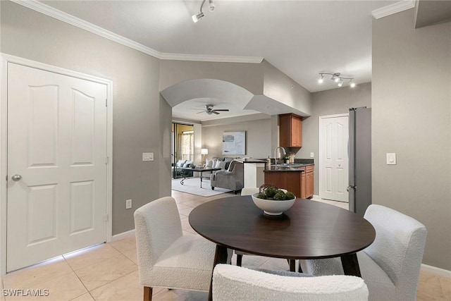 dining area featuring arched walkways, ceiling fan, light tile patterned floors, baseboards, and ornamental molding