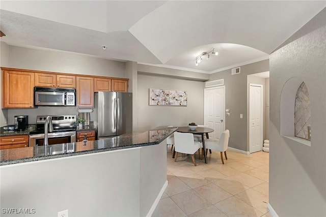 kitchen with stainless steel appliances, dark stone counters, brown cabinets, and visible vents