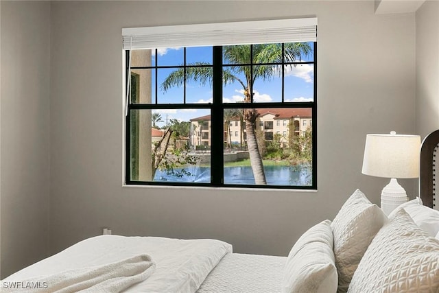 bedroom with a water view and multiple windows