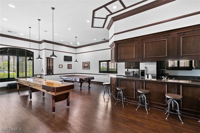 game room featuring dark wood-type flooring, a high ceiling, visible vents, and crown molding