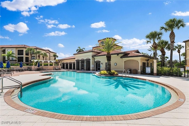 community pool with a patio area and fence