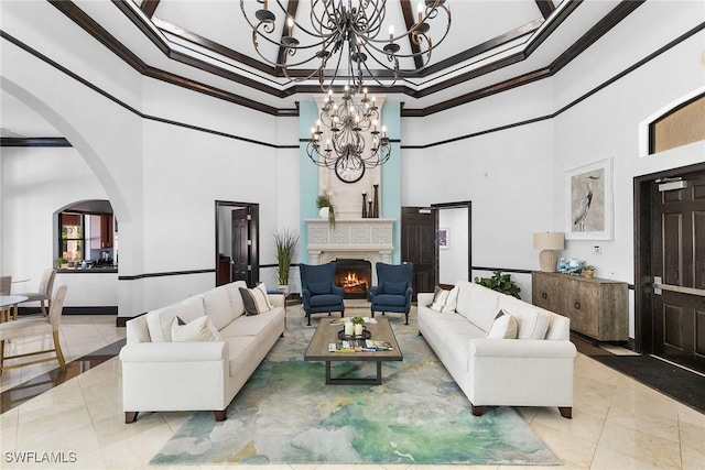 living area with arched walkways, a notable chandelier, light tile patterned floors, ornamental molding, and a warm lit fireplace