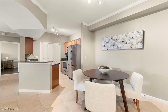 kitchen with dark countertops, light tile patterned floors, a peninsula, ornamental molding, and stainless steel appliances