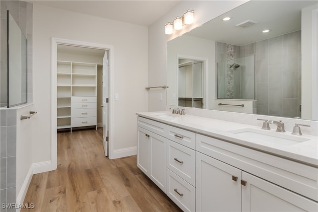 bathroom featuring hardwood / wood-style flooring, vanity, and tiled shower