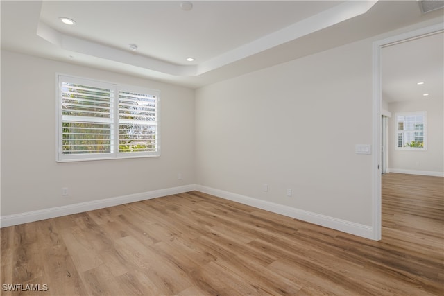 unfurnished room with a tray ceiling and light hardwood / wood-style flooring