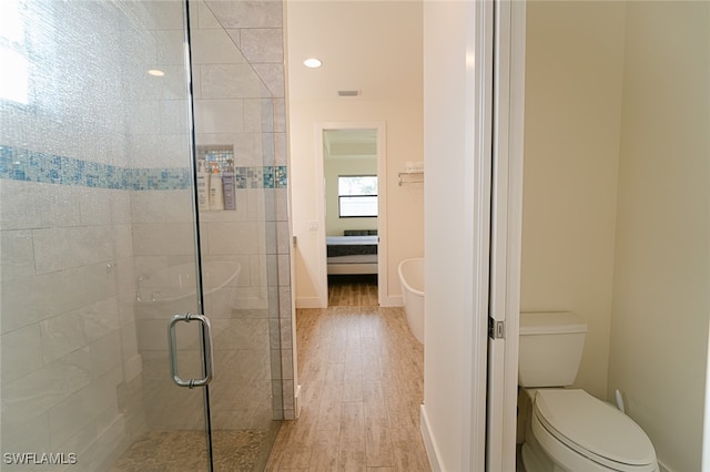 bathroom with toilet, hardwood / wood-style floors, and a shower with shower door