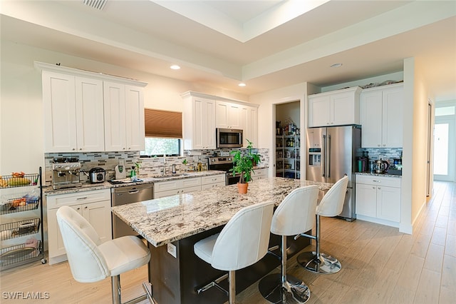 kitchen featuring white cabinetry, stainless steel appliances, tasteful backsplash, and a center island