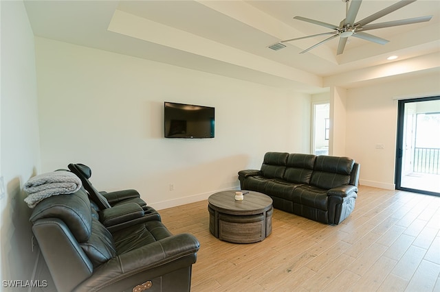 living room featuring light hardwood / wood-style floors, ceiling fan, and a tray ceiling