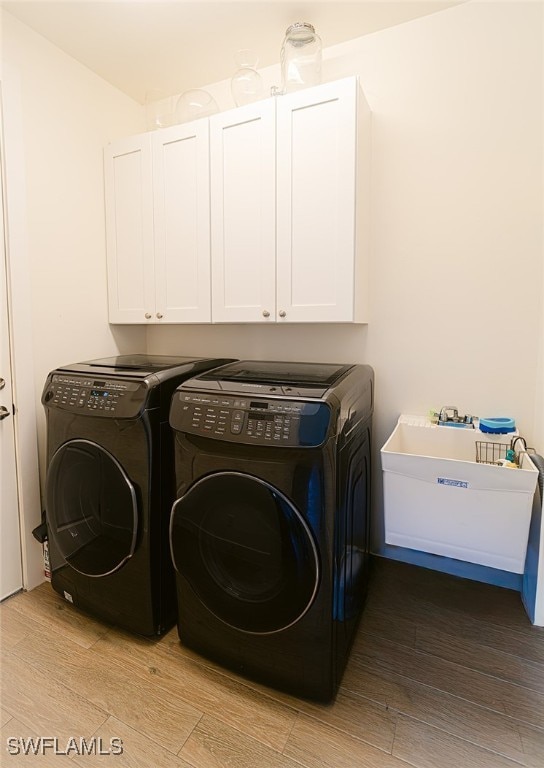 laundry area with separate washer and dryer, light hardwood / wood-style flooring, cabinets, and sink