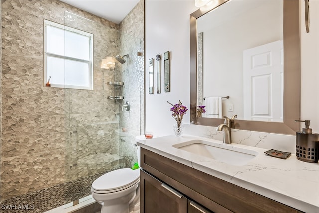 bathroom featuring toilet, vanity, and tiled shower