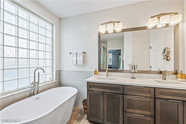 bathroom featuring tile patterned floors, vanity, a bath, and tile walls