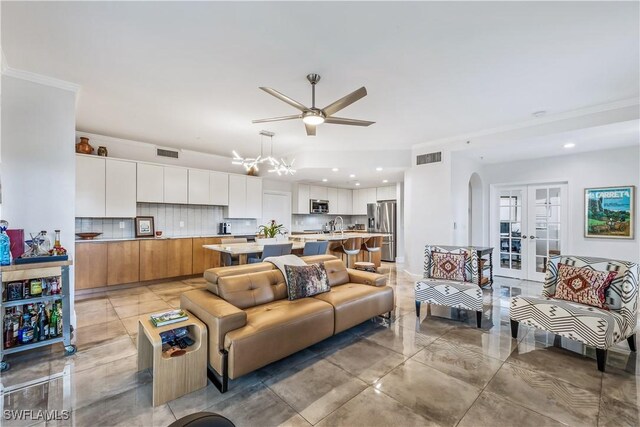 living room featuring ceiling fan with notable chandelier, crown molding, and french doors