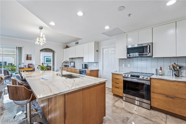 kitchen featuring a kitchen island with sink, sink, decorative backsplash, white cabinetry, and stainless steel appliances