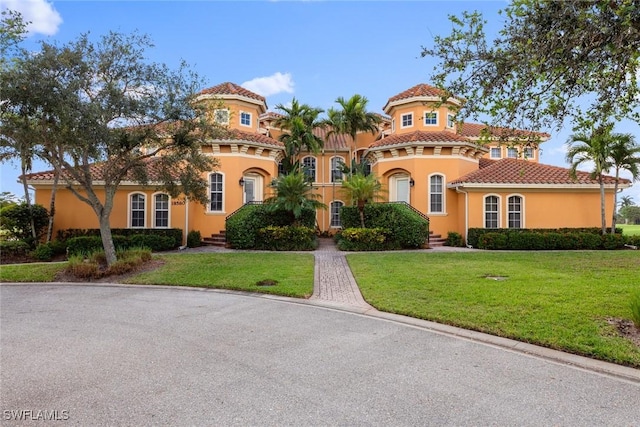 mediterranean / spanish home featuring stucco siding, a tiled roof, and a front lawn