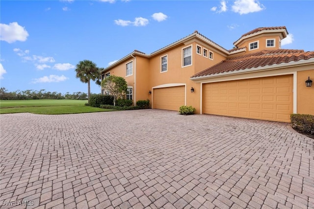 view of front of house featuring a tile roof, decorative driveway, a garage, and stucco siding