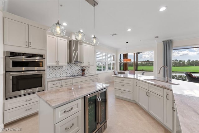 kitchen with stainless steel double oven, a sink, wine cooler, wall chimney exhaust hood, and black electric cooktop