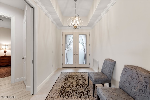 tiled foyer featuring french doors, a raised ceiling, ornamental molding, and a notable chandelier