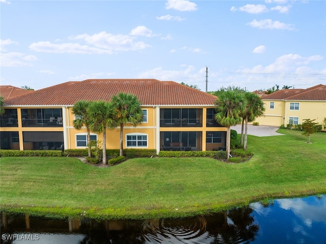 back of property featuring a lawn, a tiled roof, a water view, and stucco siding