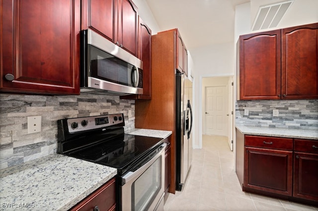 kitchen featuring stainless steel appliances, light tile patterned floors, tasteful backsplash, and light stone countertops