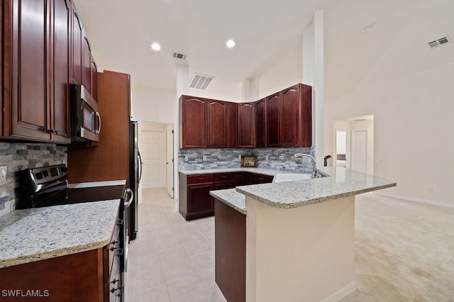 kitchen featuring kitchen peninsula, sink, a breakfast bar area, light stone countertops, and appliances with stainless steel finishes