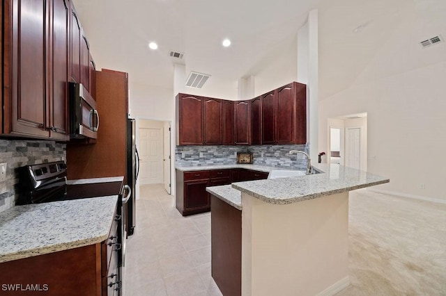 kitchen featuring sink, a breakfast bar, appliances with stainless steel finishes, light stone countertops, and kitchen peninsula