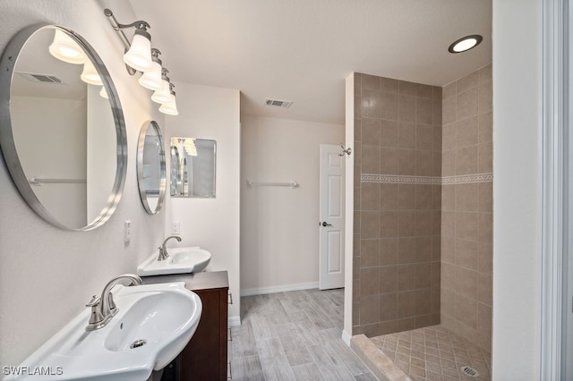 bathroom with wood-type flooring, vanity, and a tile shower